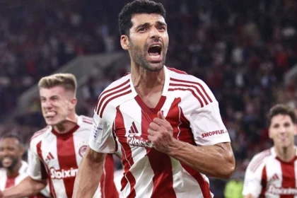 Οι παίκτες του Ολυμπιακού πανηγυρίζουν σε ευρωπαϊκό αγώνα, με φόντο τη μάχη για το Champions League.