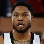 Ο Ταϊρίκ Τζόουνς στη φανέλα της Παρτιζάν, στο φόντο το σήμα του Ολυμπιακού