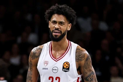 Ο Τάιλερ Ντόρσεϊ στον αέρα με σώμα εκτός ισορροπίας σουτάρει μπροστά σε δύο παίκτες του Παναθηναϊκού ενώ το χρονόμετρο δείχνει το τέλος.