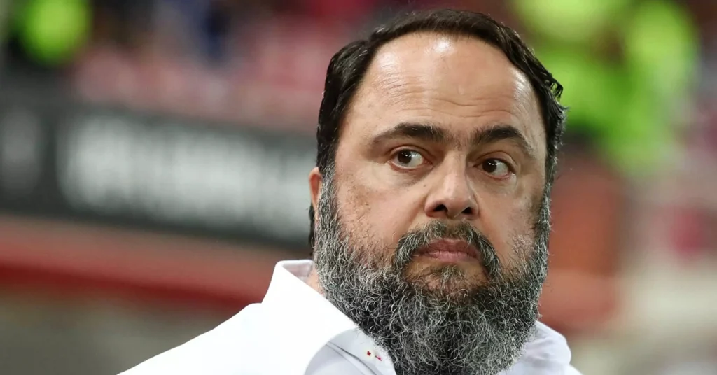 Ο Βαγγέλης Μαρινάκης πανηγυρίζει τις επιτυχίες του Ολυμπιακού με φόντο το έμβλημα των 100 χρόνων