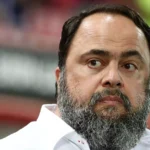 Ο Βαγγέλης Μαρινάκης πανηγυρίζει τις επιτυχίες του Ολυμπιακού με φόντο το έμβλημα των 100 χρόνων