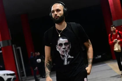 Ο Εβάν Φουρνιέ φοράει μπλουζάκι με τον Γιώργο Μπαρτζώκα να κάνει νόημα ησυχίας