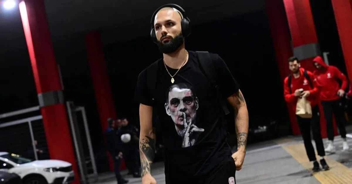 Ο Εβάν Φουρνιέ φοράει μπλουζάκι με τον Γιώργο Μπαρτζώκα να κάνει νόημα ησυχίας