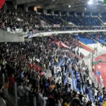 Super League με φόντο τα εμβλήματα του Ολυμπιακού, της ΑΕΚ και του ΠΑΟΚ.