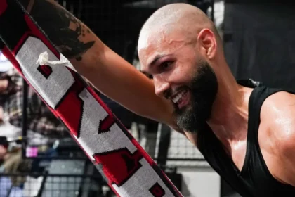 Ο Εβαν Φουρνιε κρατάει ένα ερυθρόλευκο κασκόλ του Ολυμπιακού και χαμογελάει με πάθος προς την εξέδρα των οπαδών στο Παρίσι