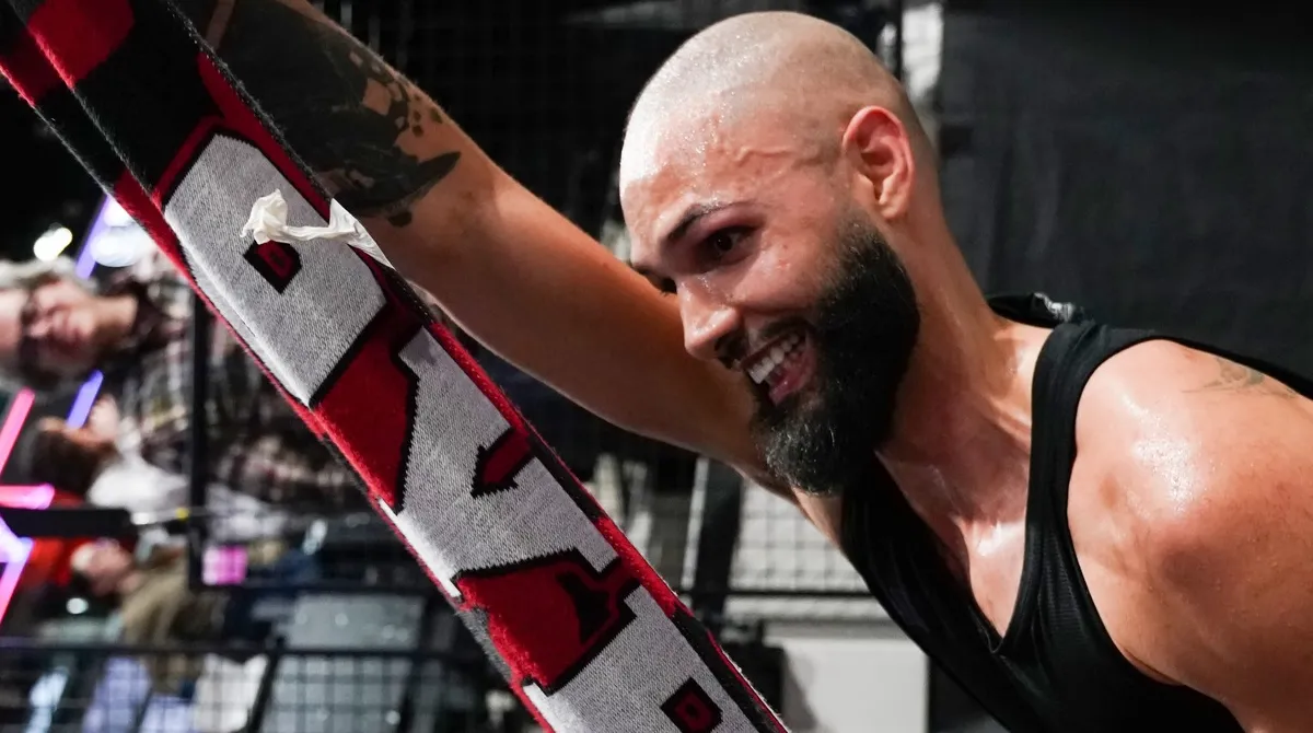 Ο Εβαν Φουρνιε κρατάει ένα ερυθρόλευκο κασκόλ του Ολυμπιακού και χαμογελάει με πάθος προς την εξέδρα των οπαδών στο Παρίσι