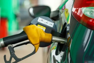 Κίτρινη αντλία βενζίνης την ώρα που γεμίζει το ρεζερβουάρ ενός αυτοκινήτου, εν μέσω της νέας αύξησης τιμών στα καύσιμα.