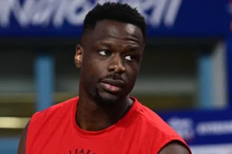 Ο Μουστάφα Φαλ με τη φανέλα του Ολυμπιακού παρακολουθεί την εξέλιξη αγώνα της Euroleague.