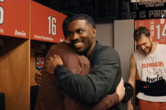 Ο Κίναν Έβανς χαμογελαστός με τα ρούχα του Ολυμπιακού κατά την ξαφνική επιστροφή του στην Ελλάδα και την ομάδα.